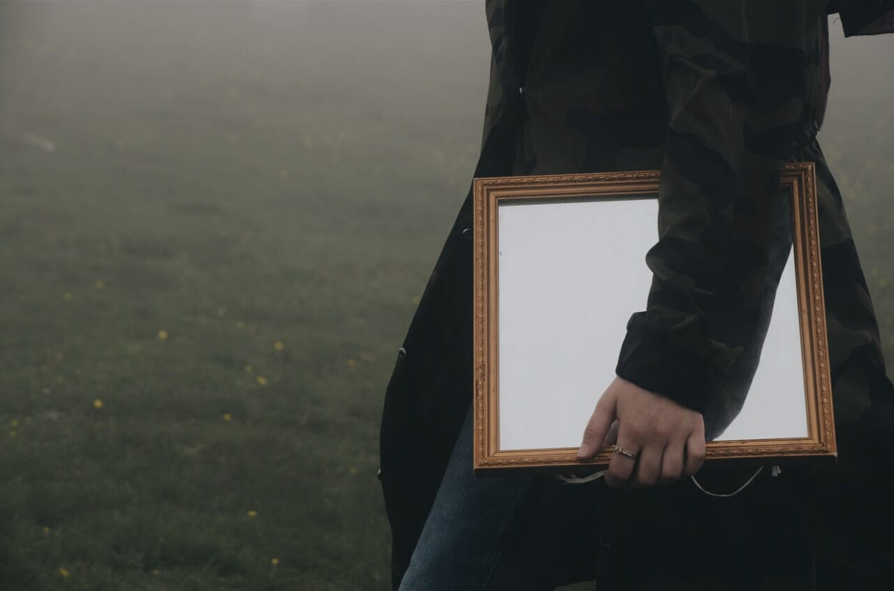 man holding brown framed mirror