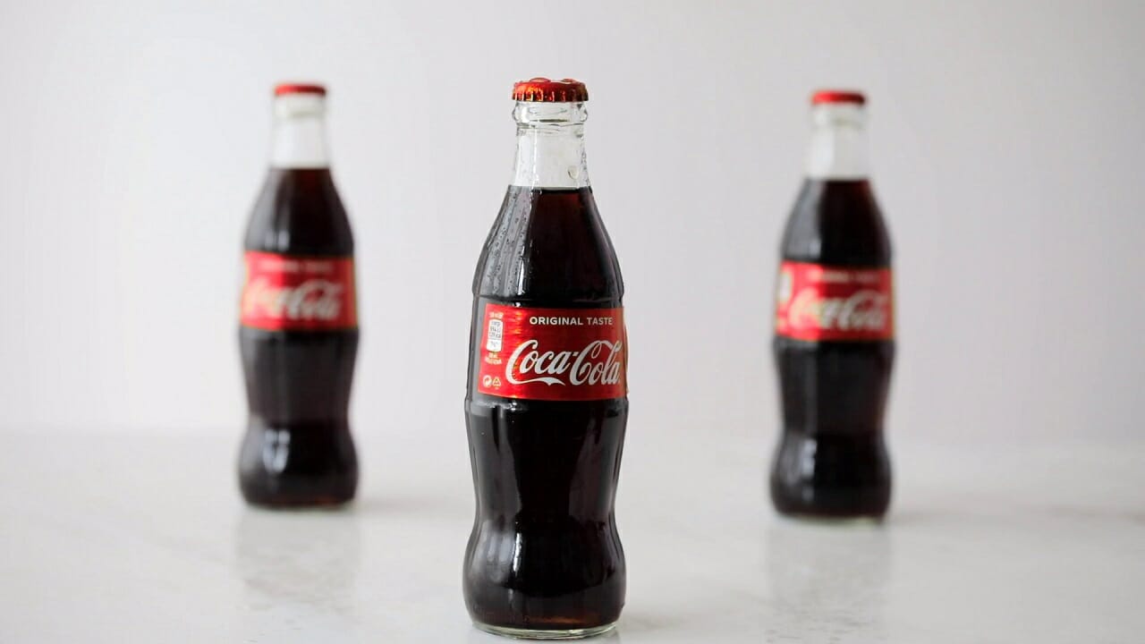 three coca cola bottles isolated on gray background